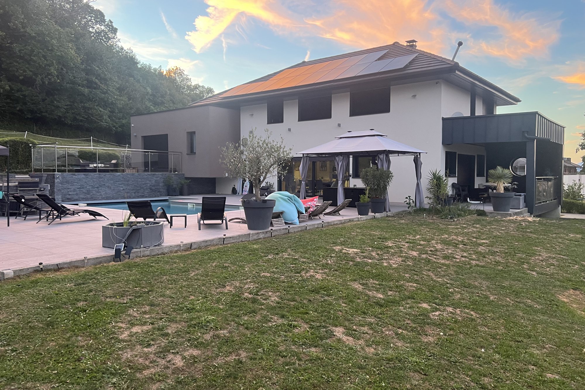 La villa contemporaine et son jardin sous un ciel de fin de journée